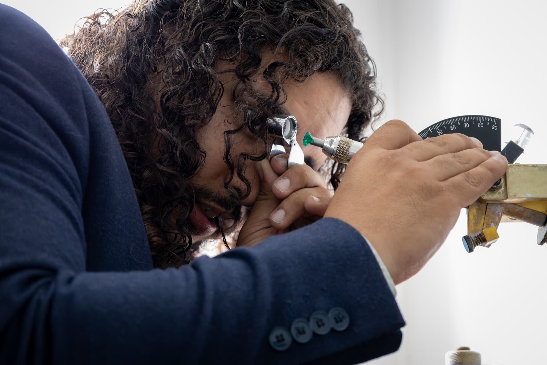 A jeweler inspecting a cut stone through a loupe